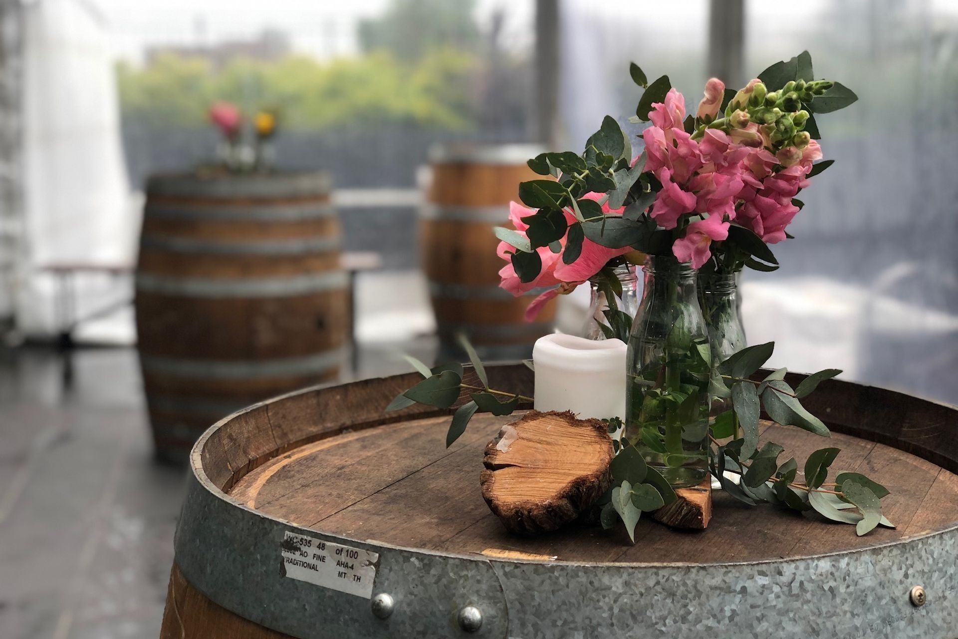 A wooden barrel with a vase of flowers and a candle on it.