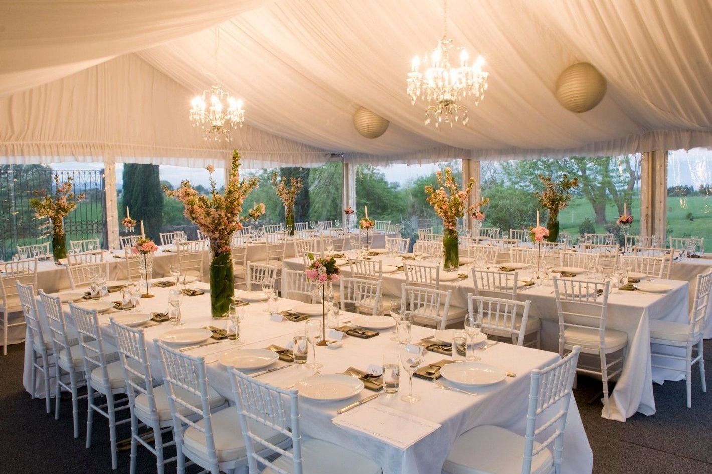 A large tent with tables and chairs set up for a wedding reception.