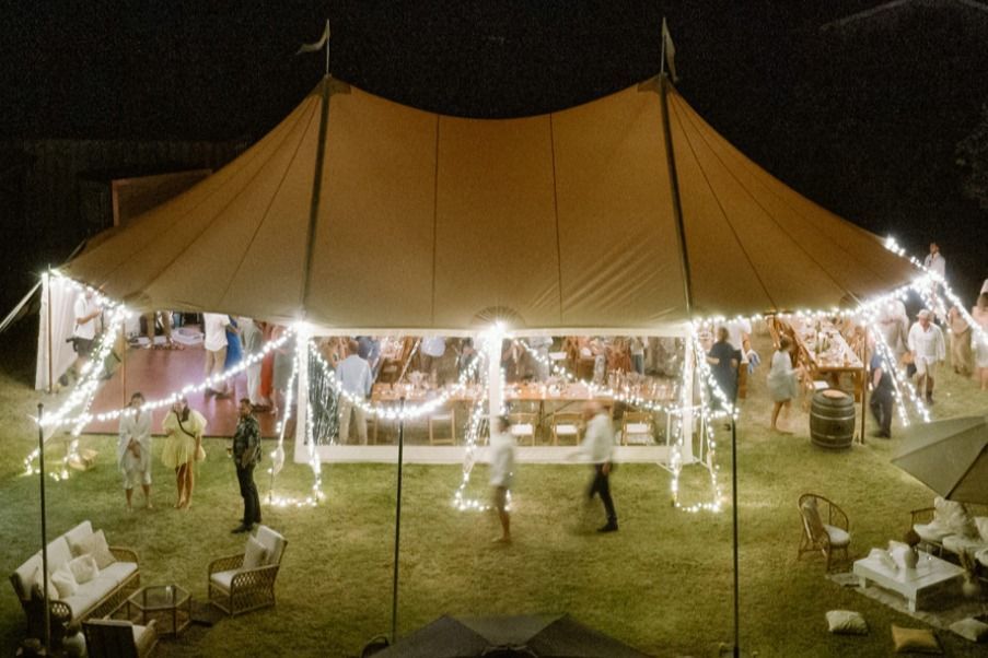 A group of people are standing outside of a tent at night.