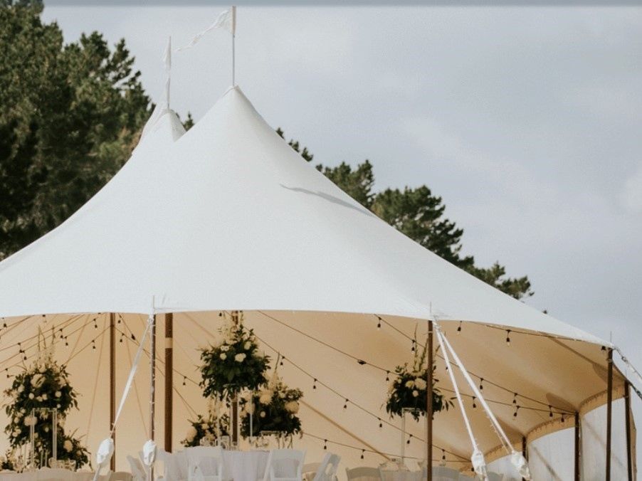 A large white tent with tables and chairs underneath it.