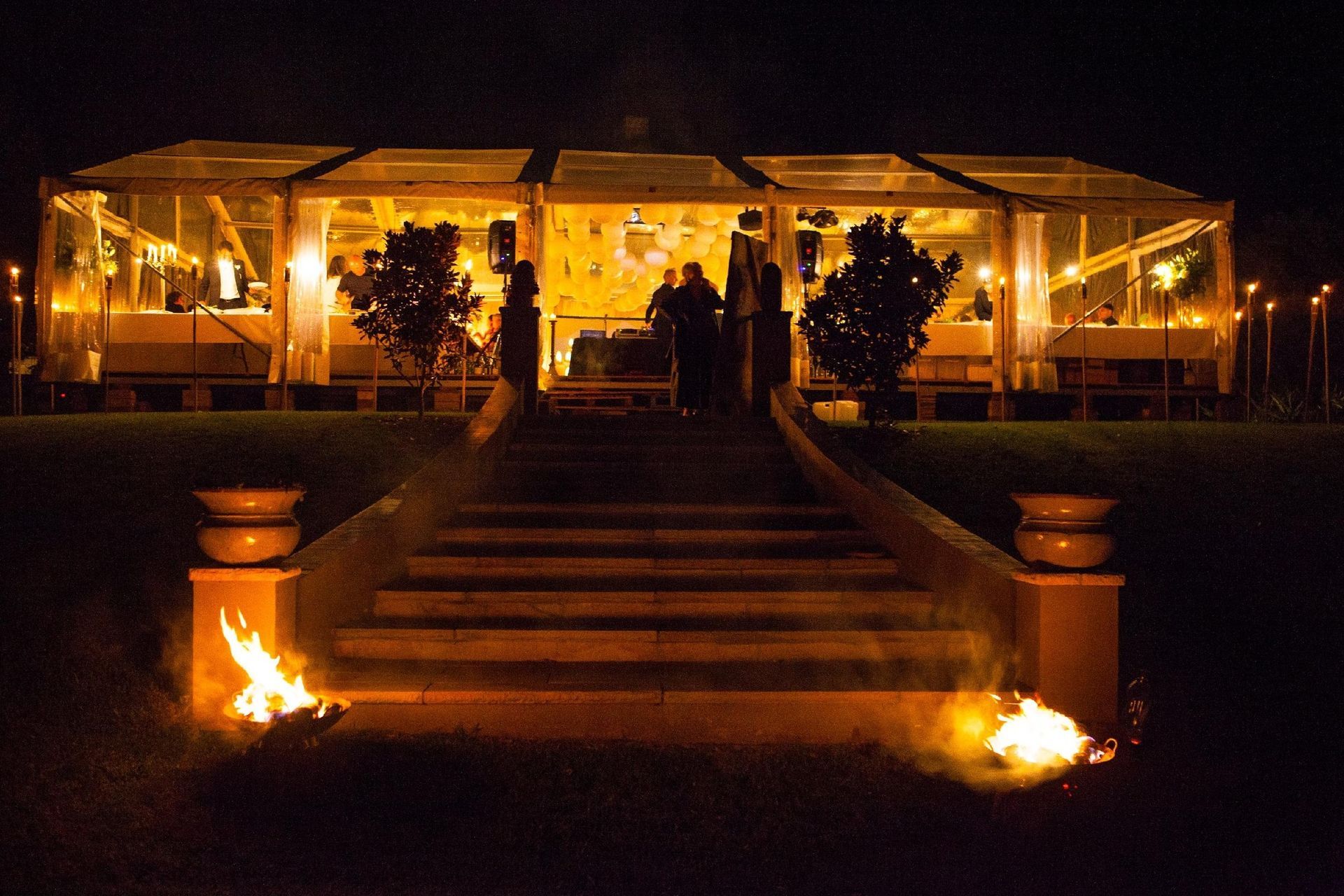 A large tent is lit up at night with stairs leading up to it