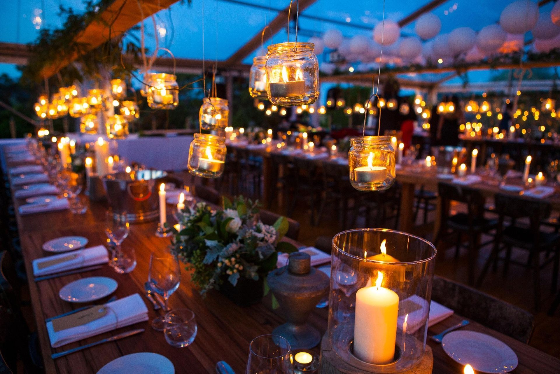 A long wooden table with candles and flowers on it.