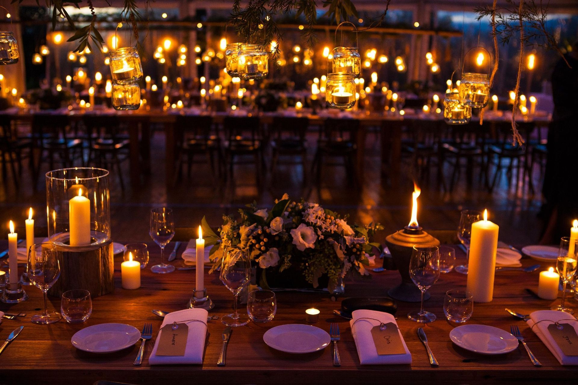 A long wooden table with candles and flowers on it.