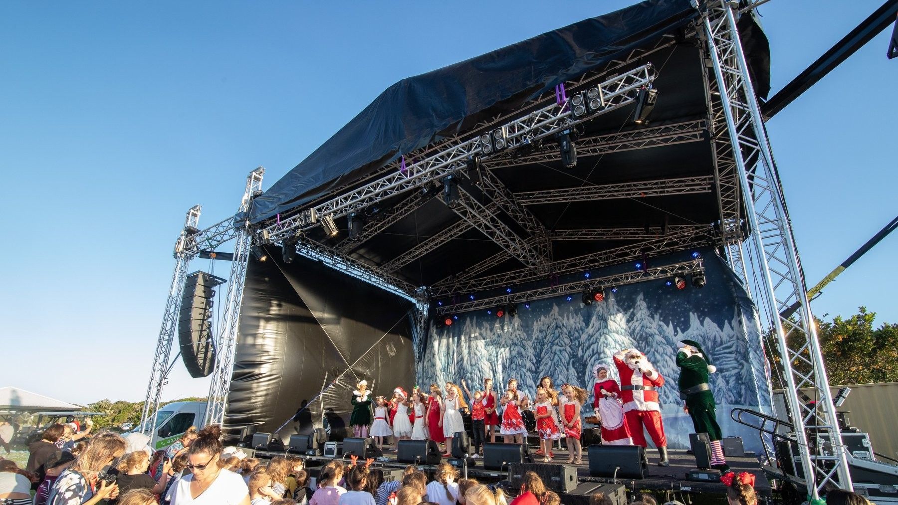 A large stage is being set up for a concert in a park.