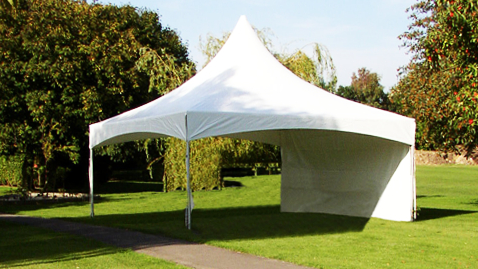 A white tent is sitting in the middle of a grassy field