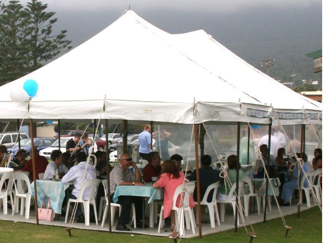A group of people are sitting under a white tent