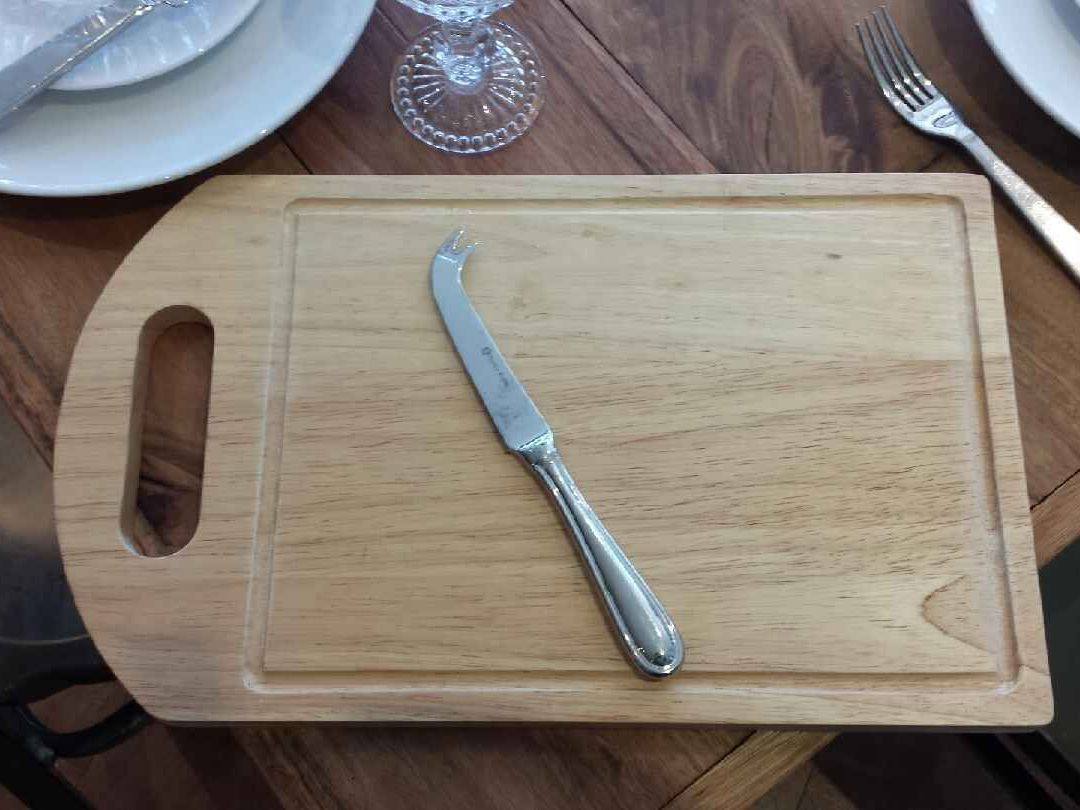 A cheese knife over a wooden chopping board