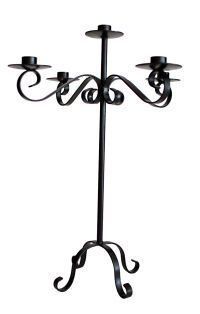 A black wrought iron candle holder with three candles on a white background.