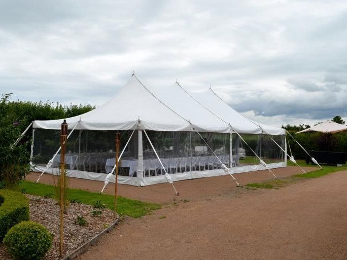 A large white tent is sitting on the side of a dirt road.