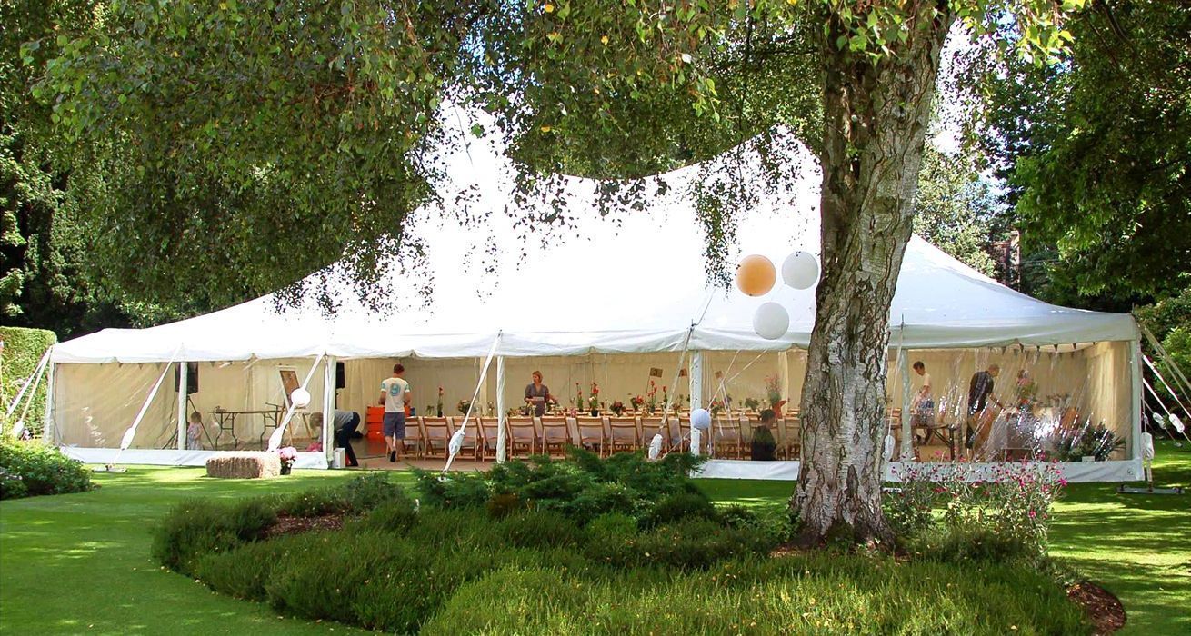 A large white tent is sitting in the middle of a lush green field.