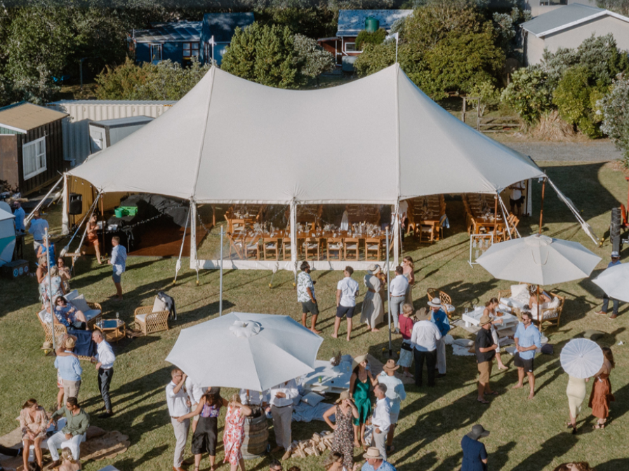 An aerial view of a large tent filled with people and umbrellas.