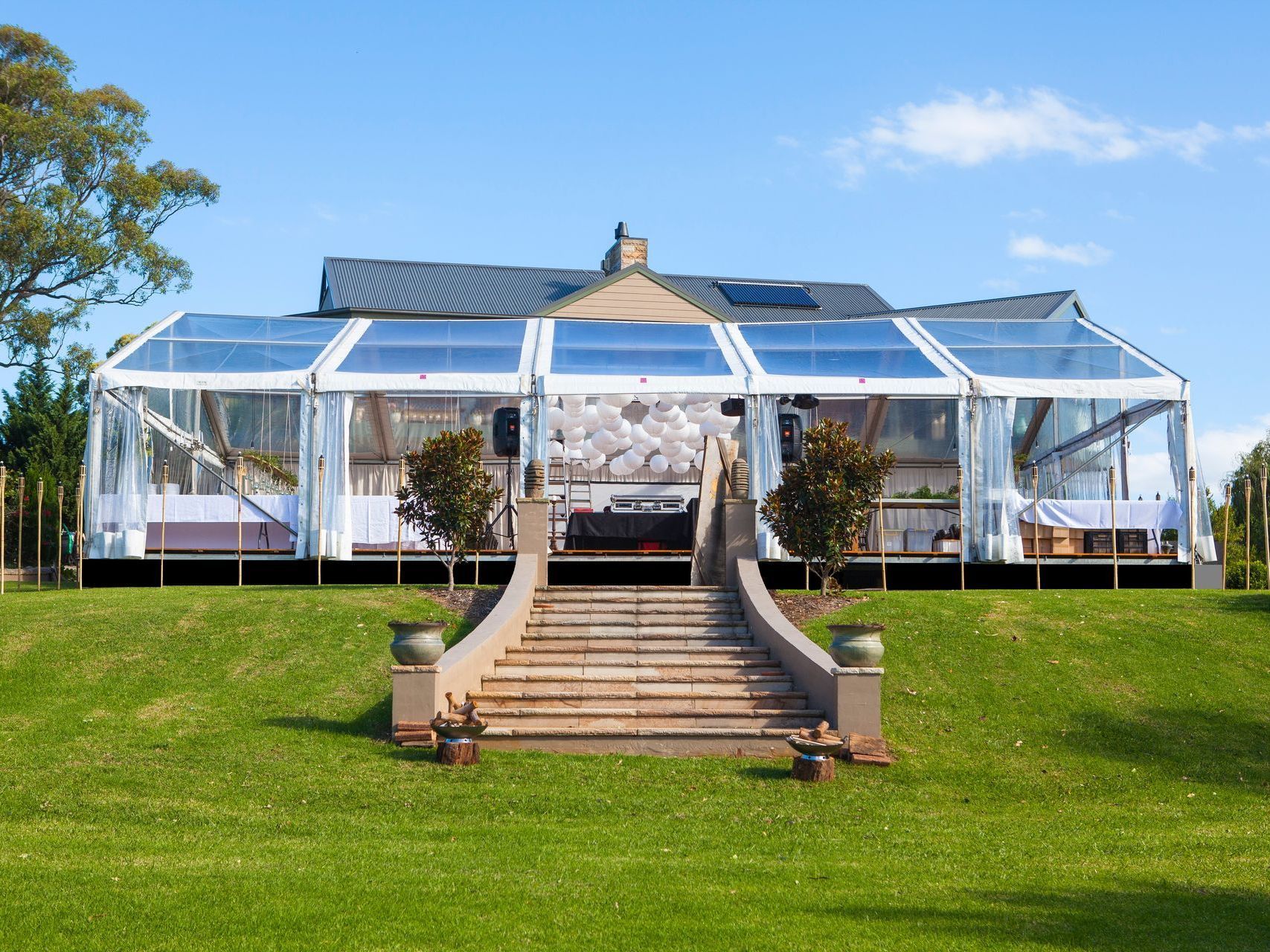 A large clear tent is sitting on top of a grassy hill.