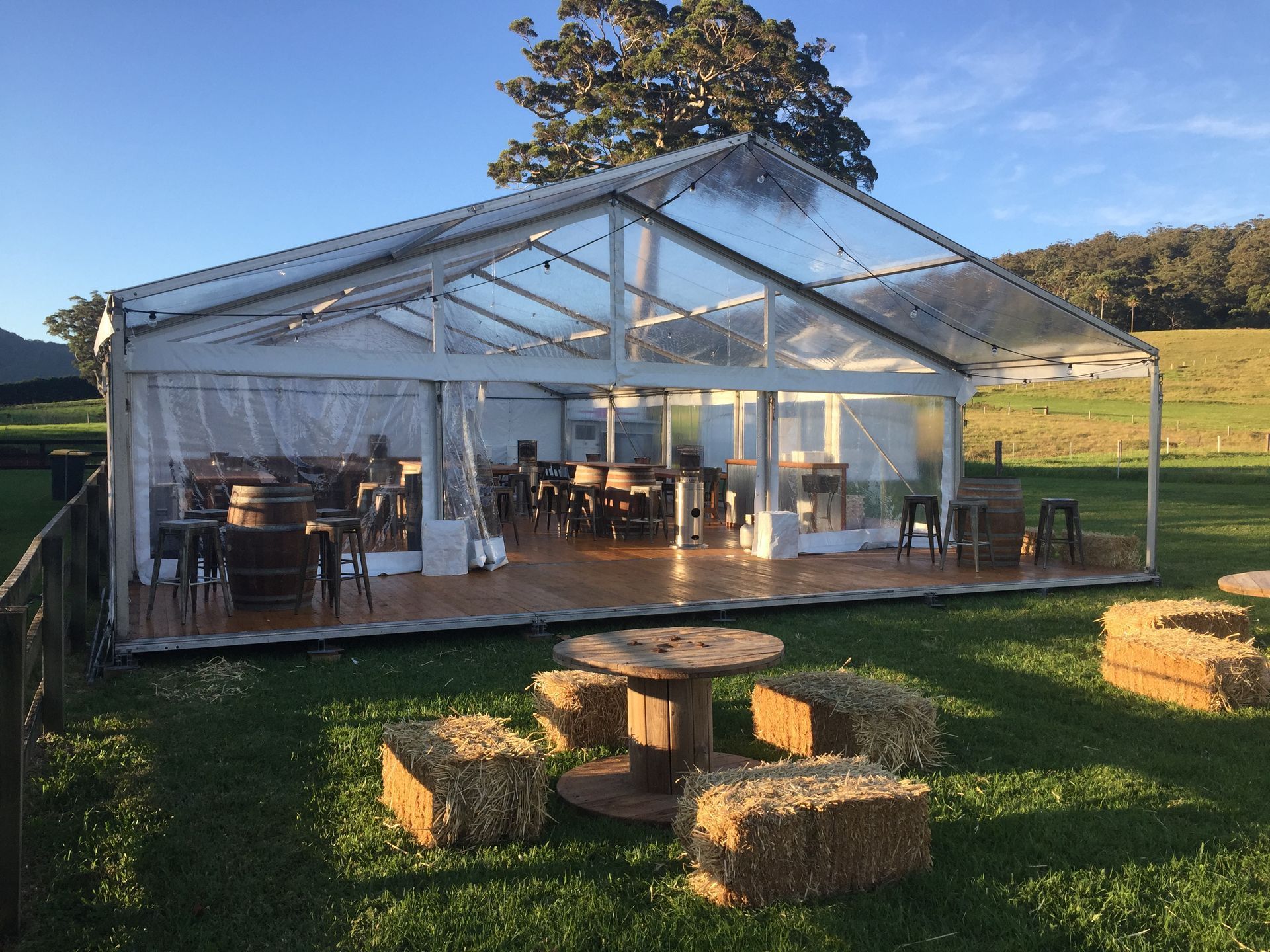 A clear tent is sitting in the middle of a grassy field.