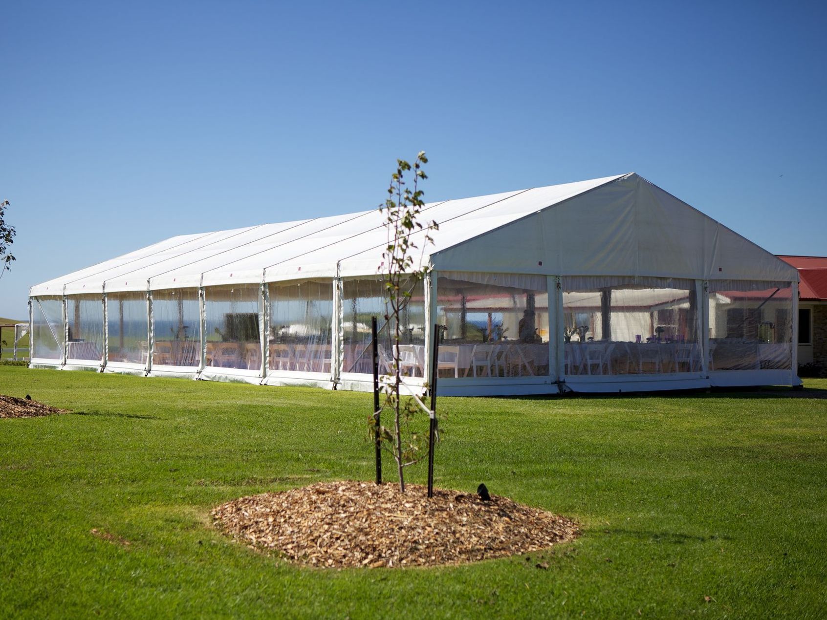 A large white tent is sitting in the middle of a lush green field.