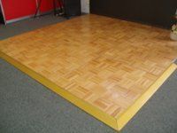 A wooden dance floor with a yellow border in a room.