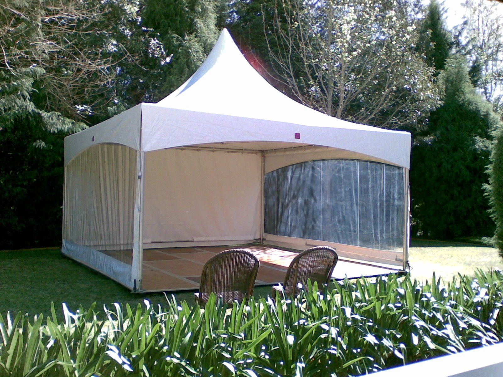 A white tent is sitting in the middle of a lush green field