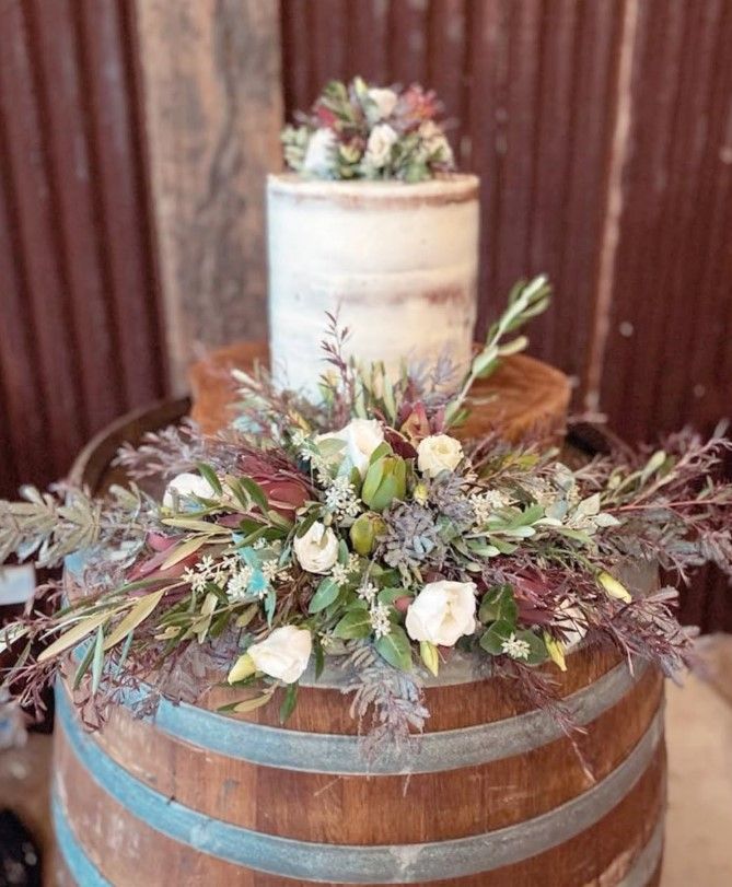 A wedding cake is sitting on top of a wooden barrel.