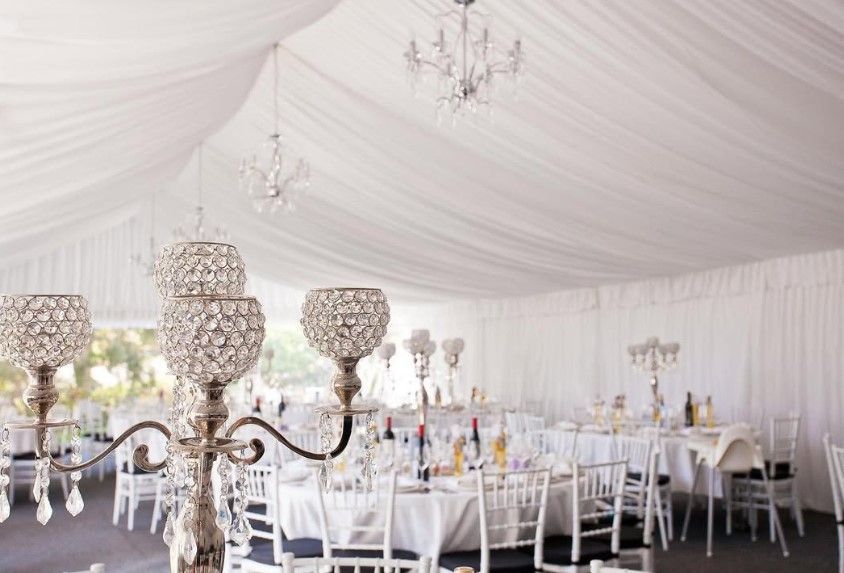 A white tent with tables and chairs set up for a wedding reception