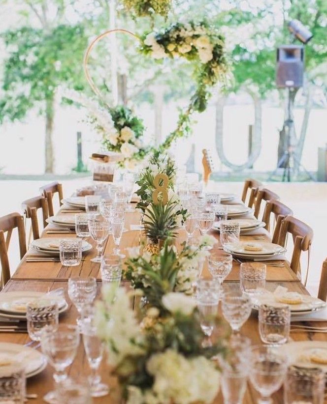 A long table with plates , glasses , and flowers on it.