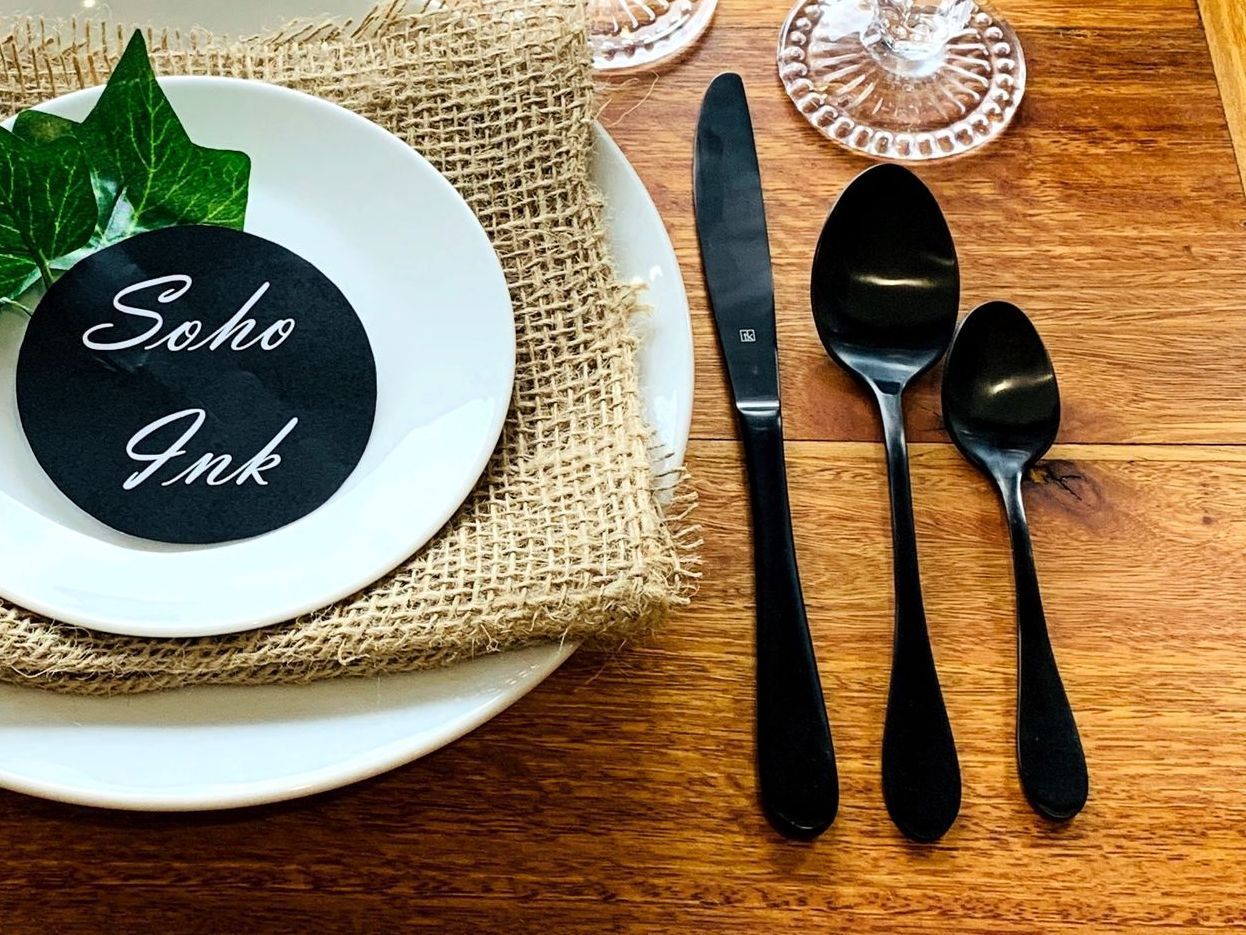 A set of cutlery and plates with Soho Ink words on it