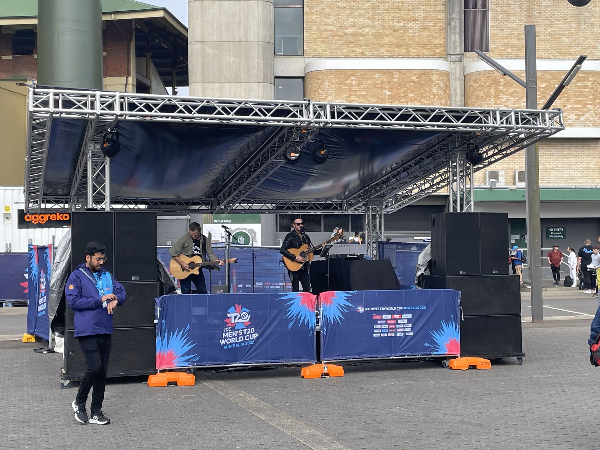A wedding ceremony is taking place in the grass with white chairs and a white carpet.
