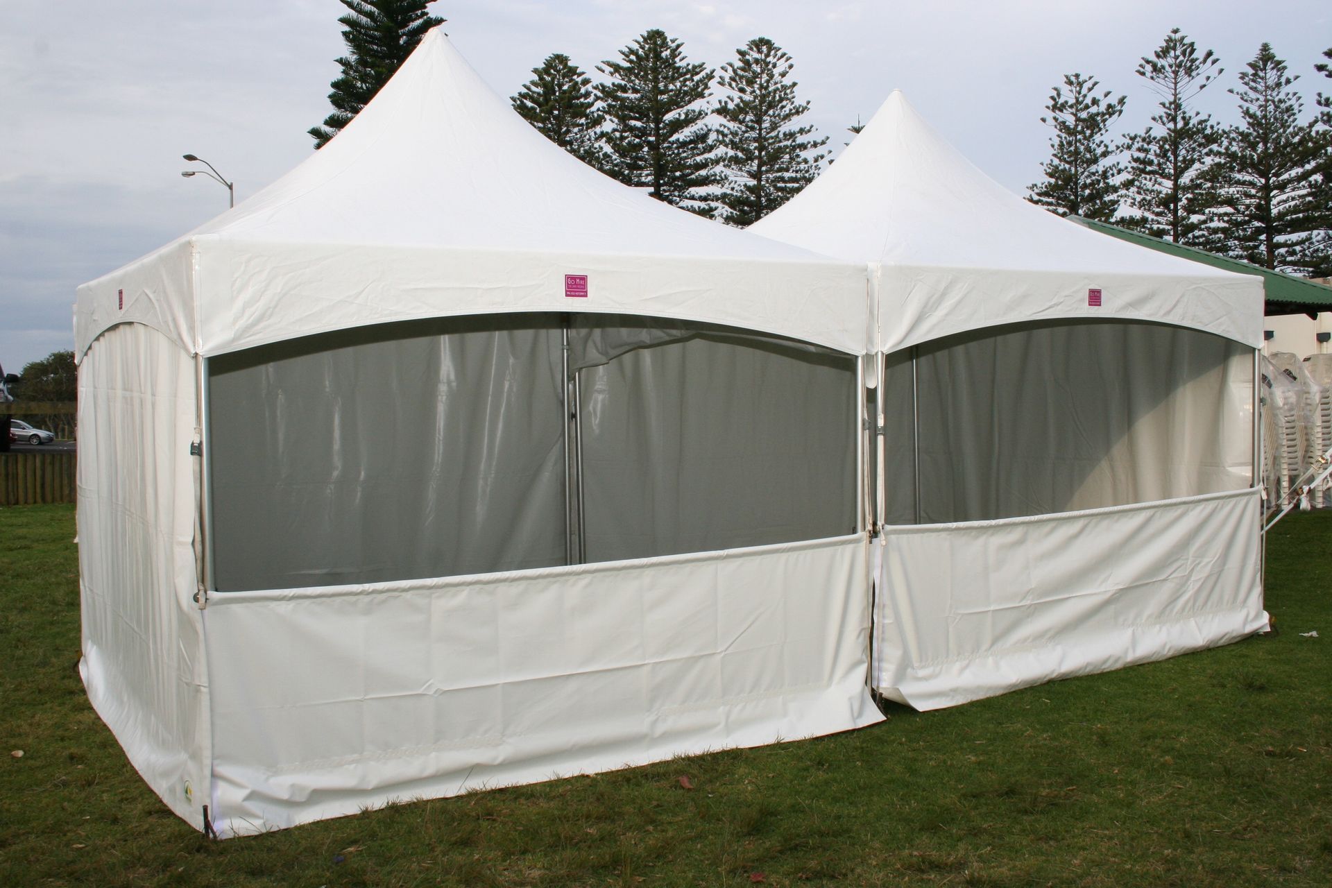 A white tent is sitting in the grass with trees in the background