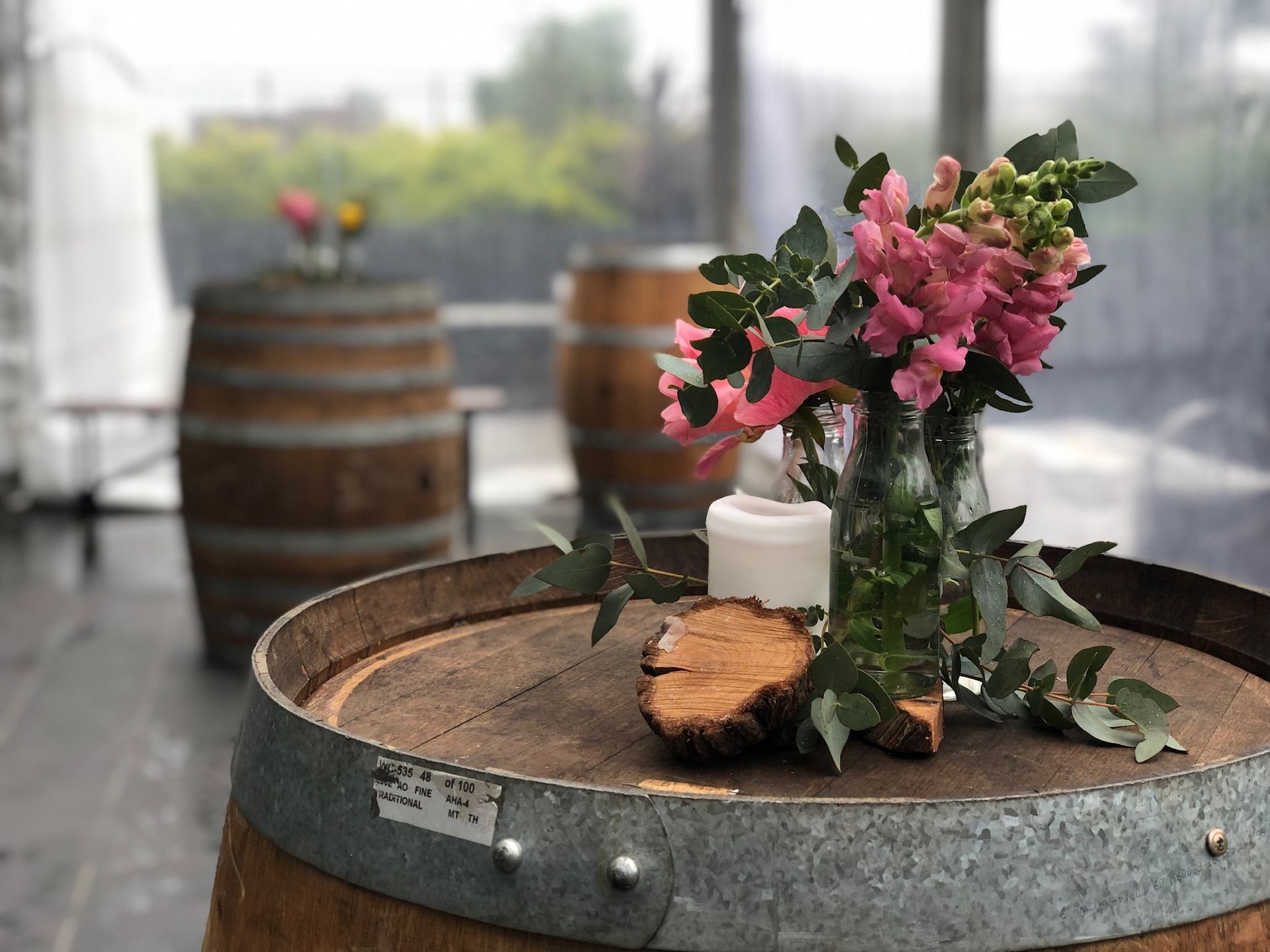 A wooden barrel with a vase of flowers and a candle on it.