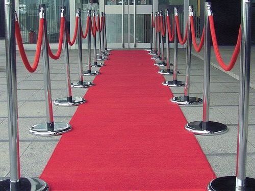 A row of red rope barriers along a red carpet