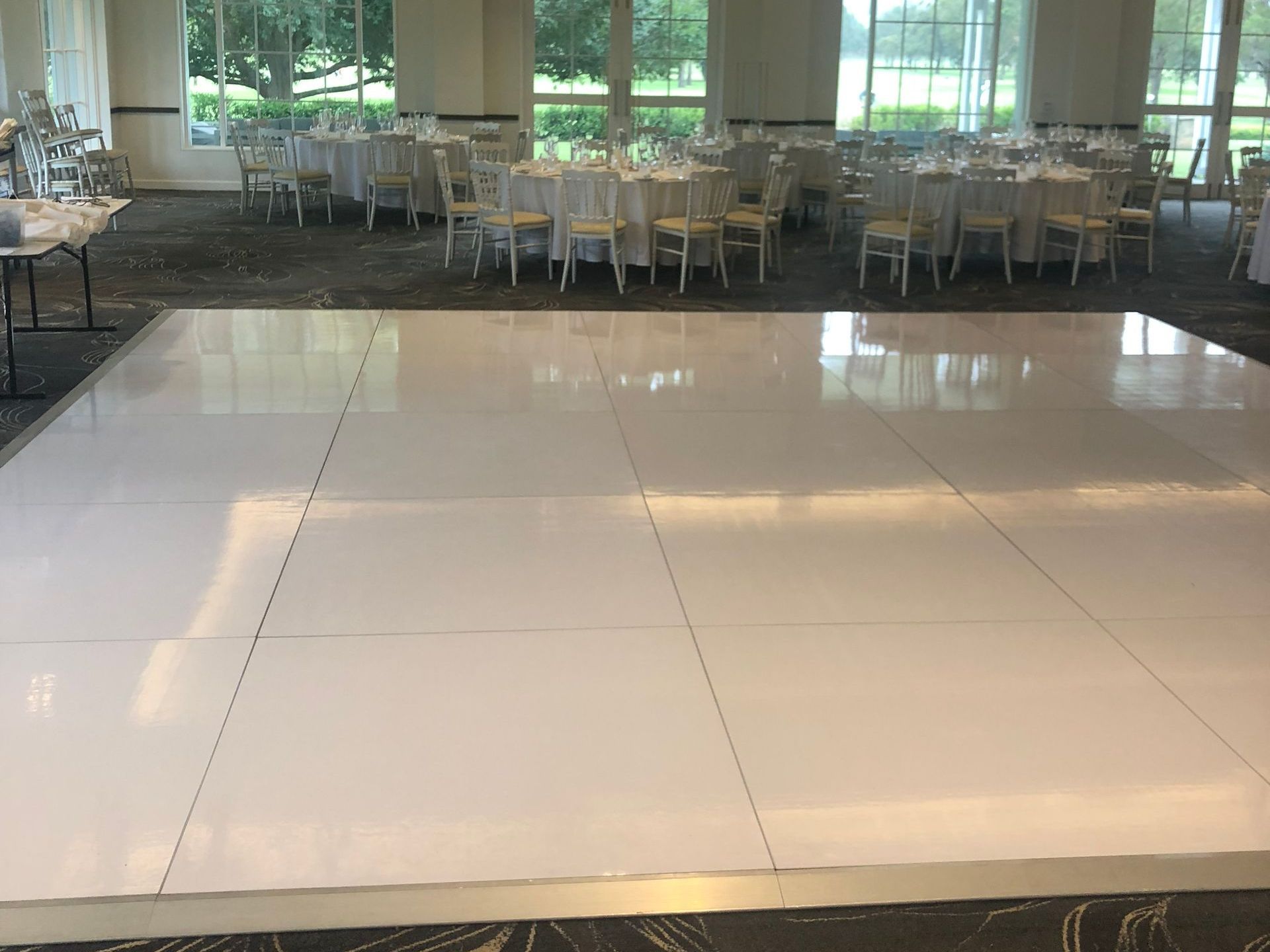 A large room with tables and chairs and a white dance floor.