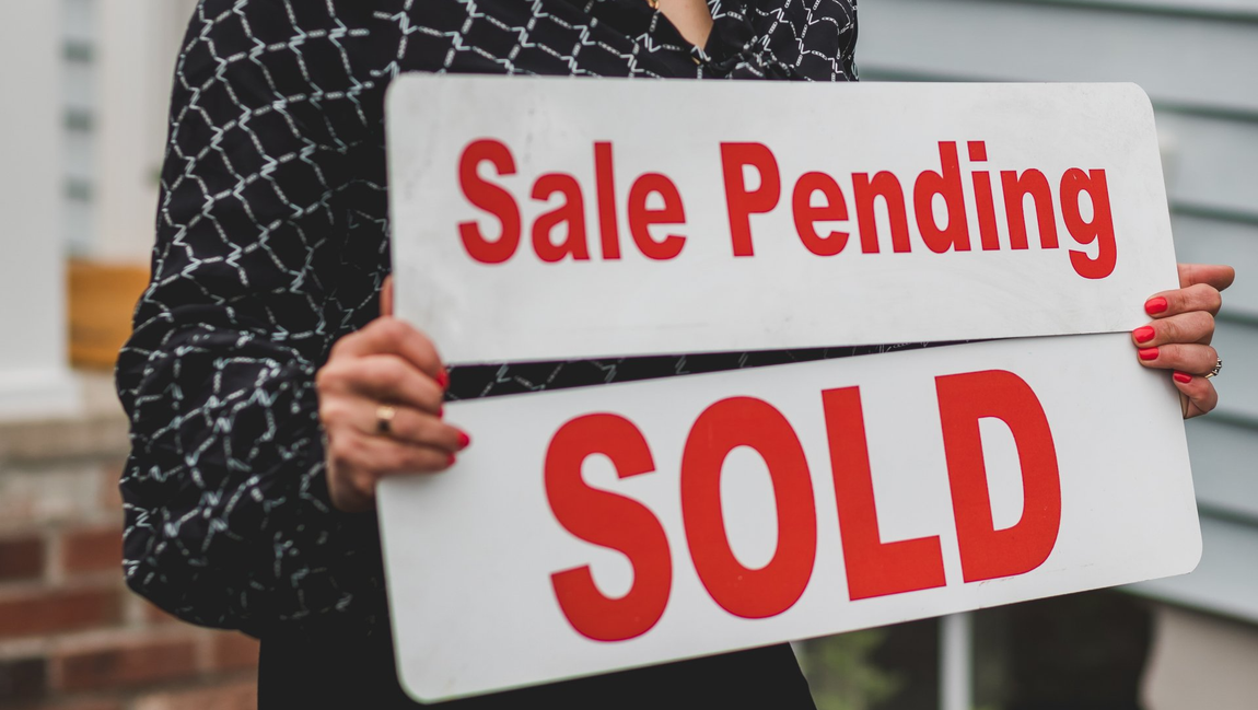 Real estate yard signs on post marking successful home sale in Chicagoland neighborhood. 