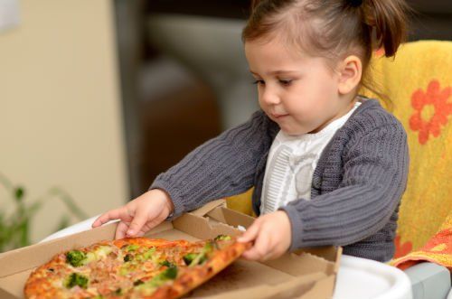 Bambina piccola  cogliendo la pizza
