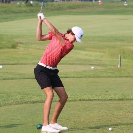 A group of women in purple shirts and white skirts are posing for a picture on a golf course.
