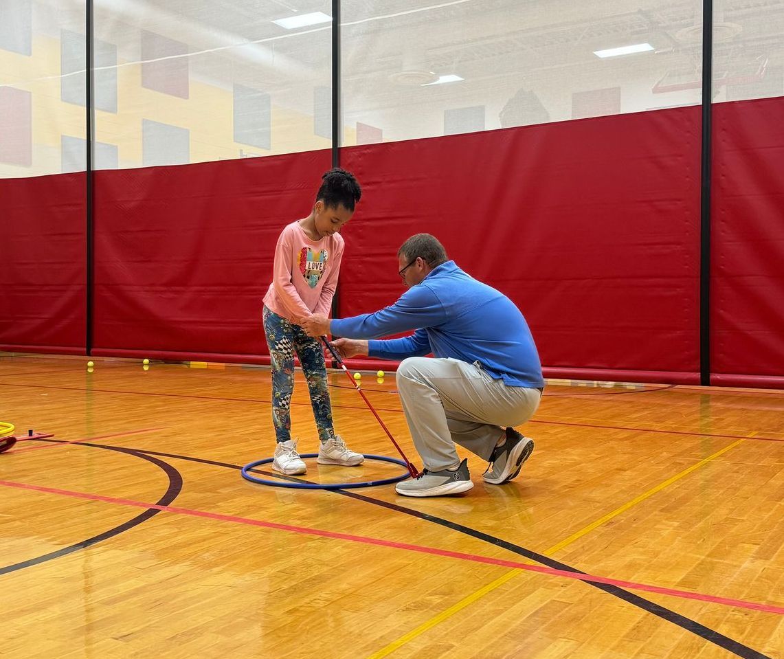 A man and a little girl are playing tennis on a court.