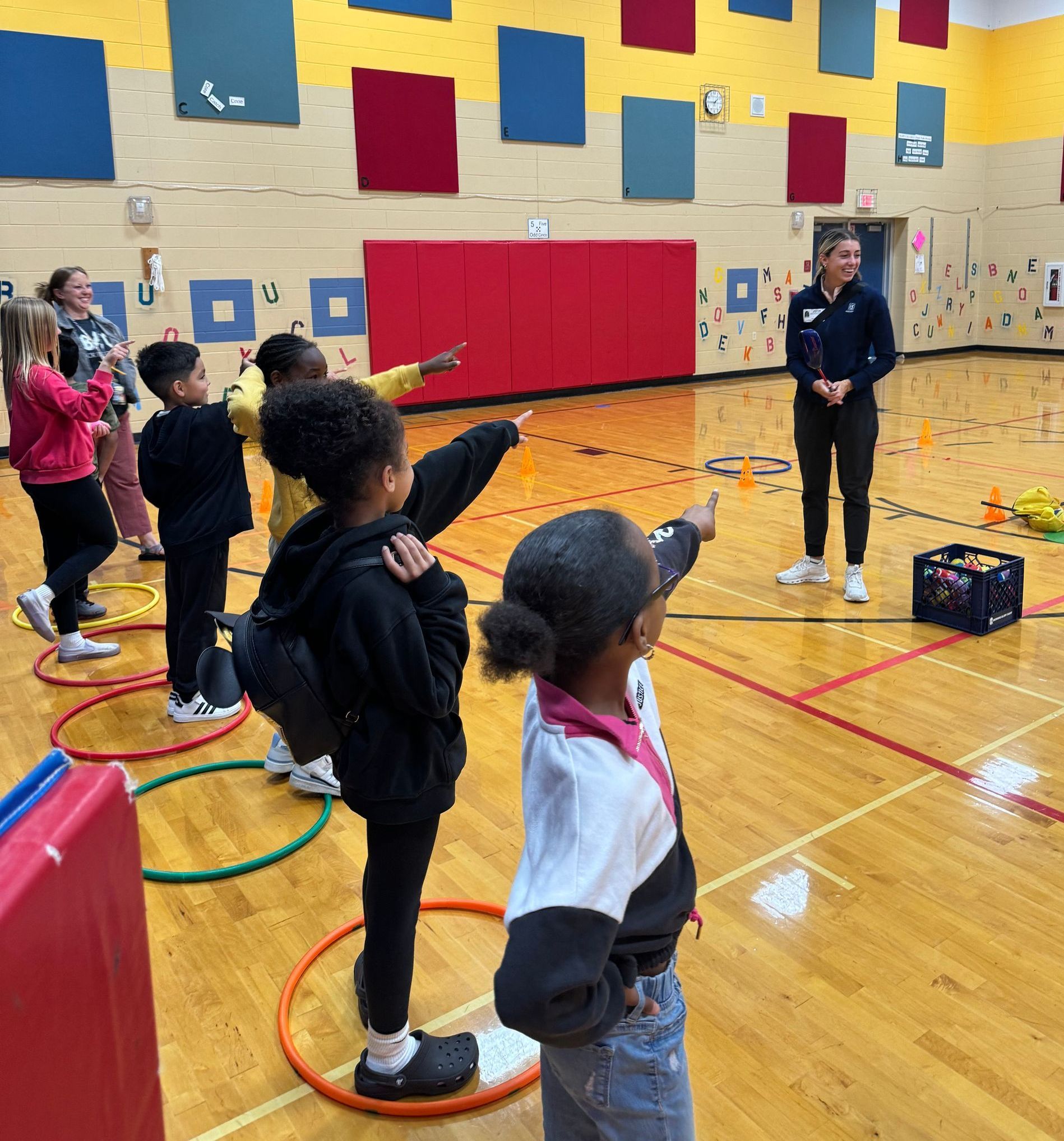 A group of children are playing with hula hoops in a gym.