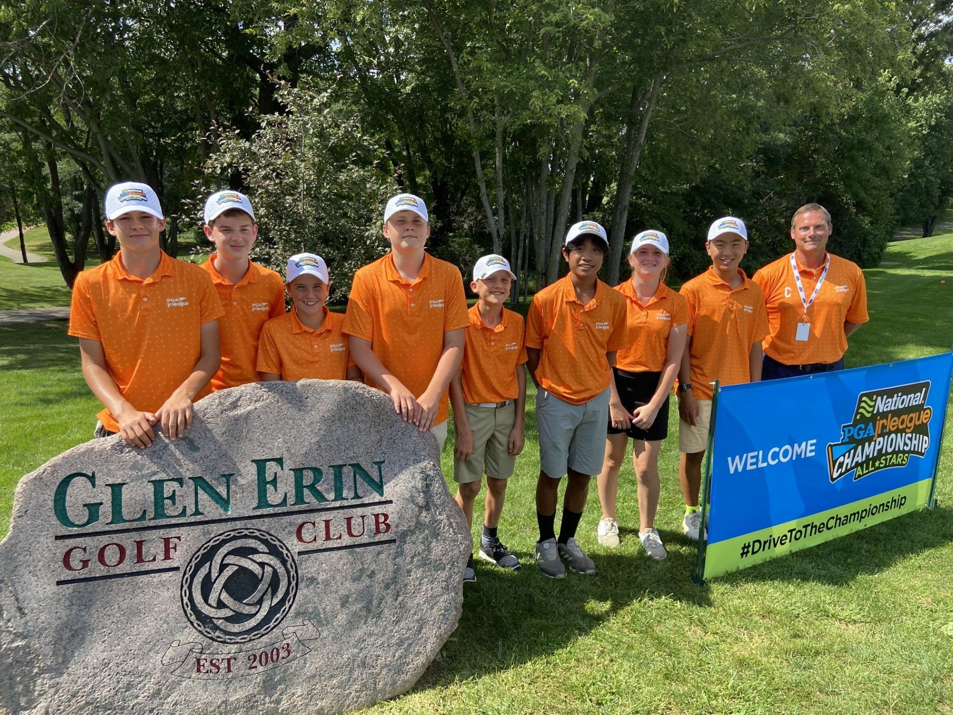 A group of young men are posing for a picture in front of a golf club sign.