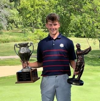 A young man is holding a trophy and a statue of a golfer on a golf course.