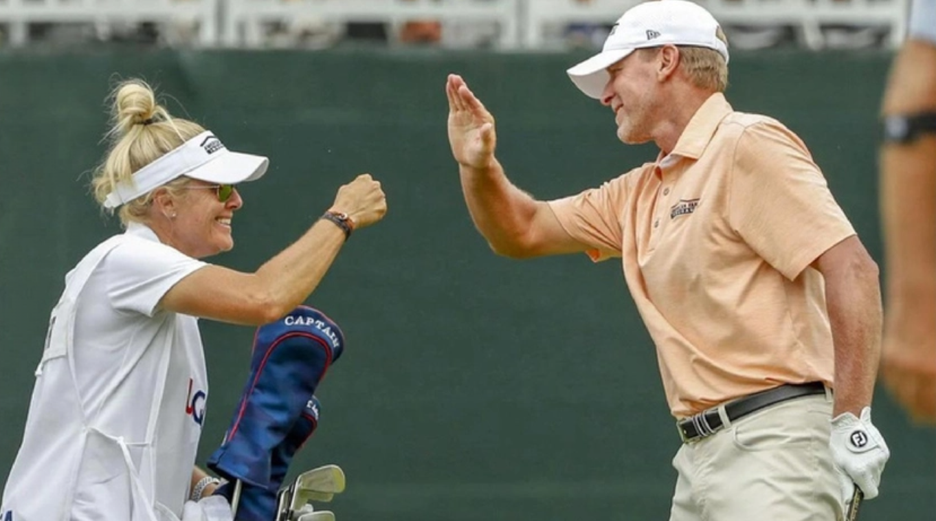 A man and a woman are giving each other a high five on a golf course.