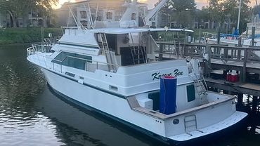 A white boat is docked at a dock in the water.