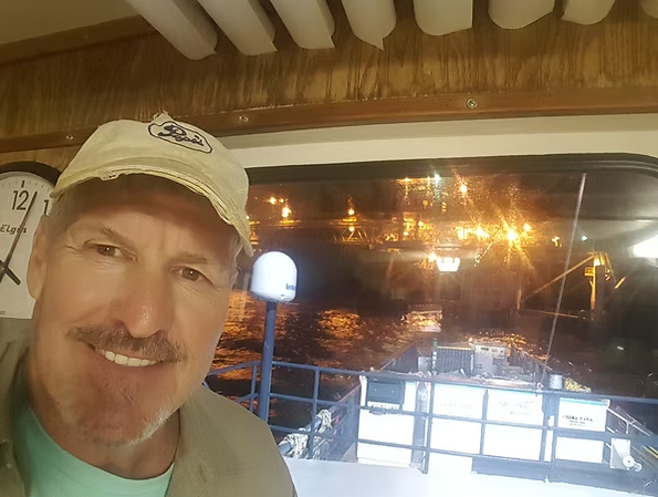 A man is taking a selfie on a boat at night.