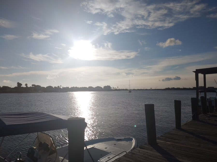 A boat is docked at a dock with the sun shining on the water
