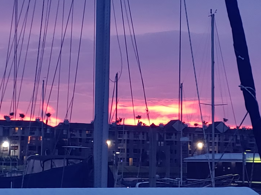 A sunset over a harbor with boats in the foreground