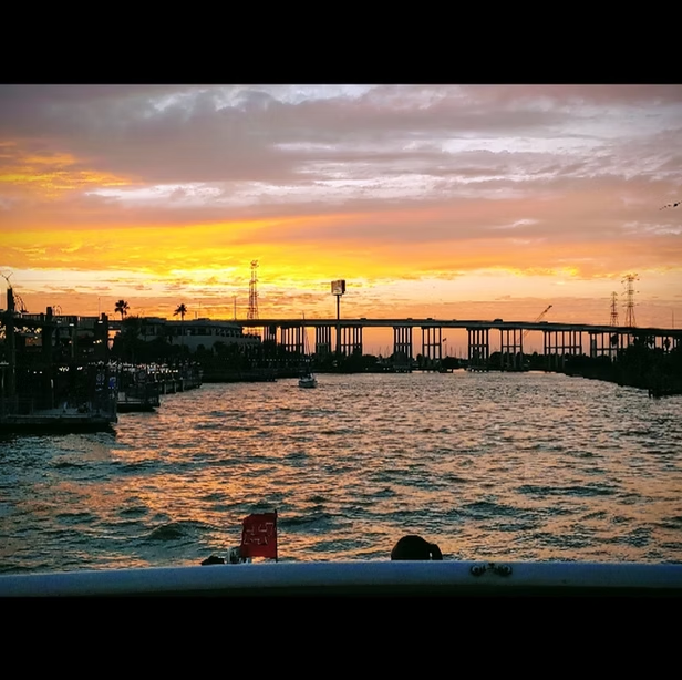 A sunset over a body of water with a bridge in the background.
