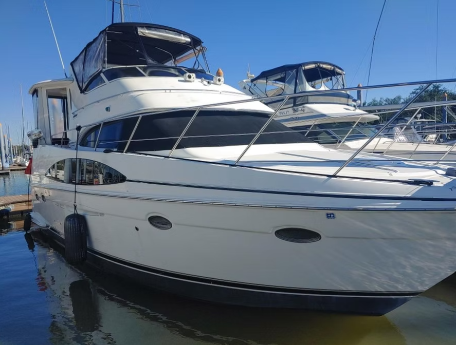 A large white boat is docked in a marina.