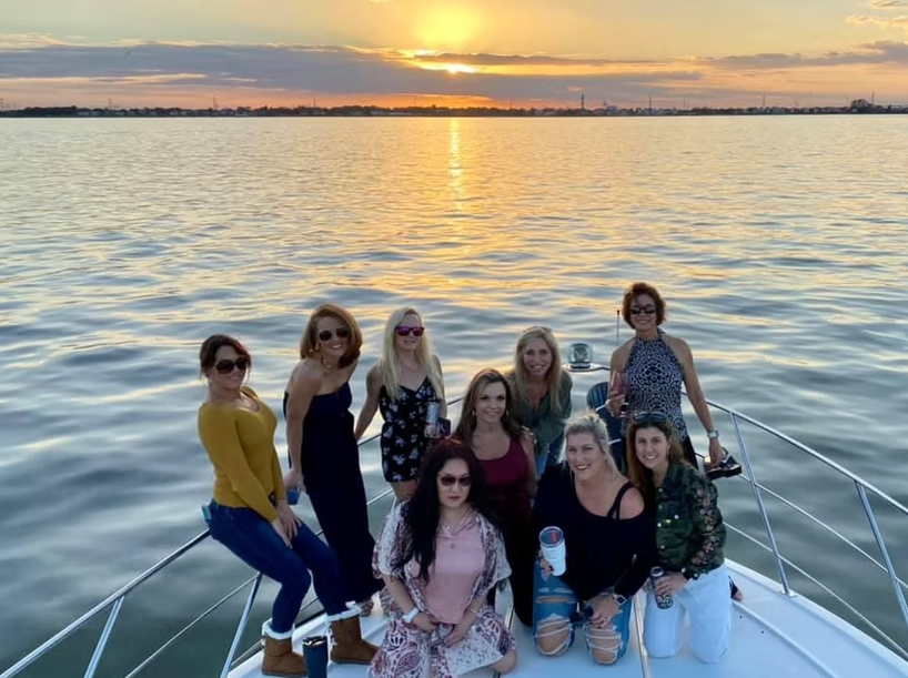 A group of women are posing for a picture on a boat in the water.