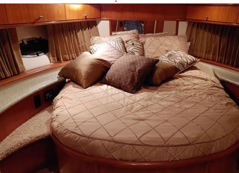 A bed with a round mattress and pillows on a boat.