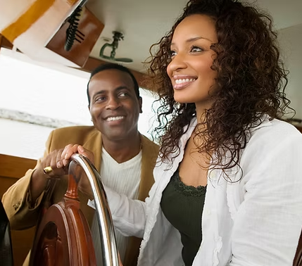 A man and a woman are sitting at the steering wheel of a boat