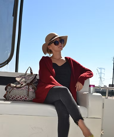 A woman wearing a hat and sunglasses is sitting on a boat