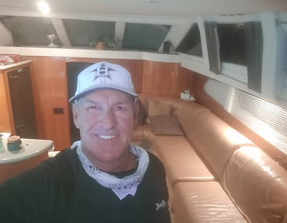 A man wearing a hat is taking a selfie in a boat.