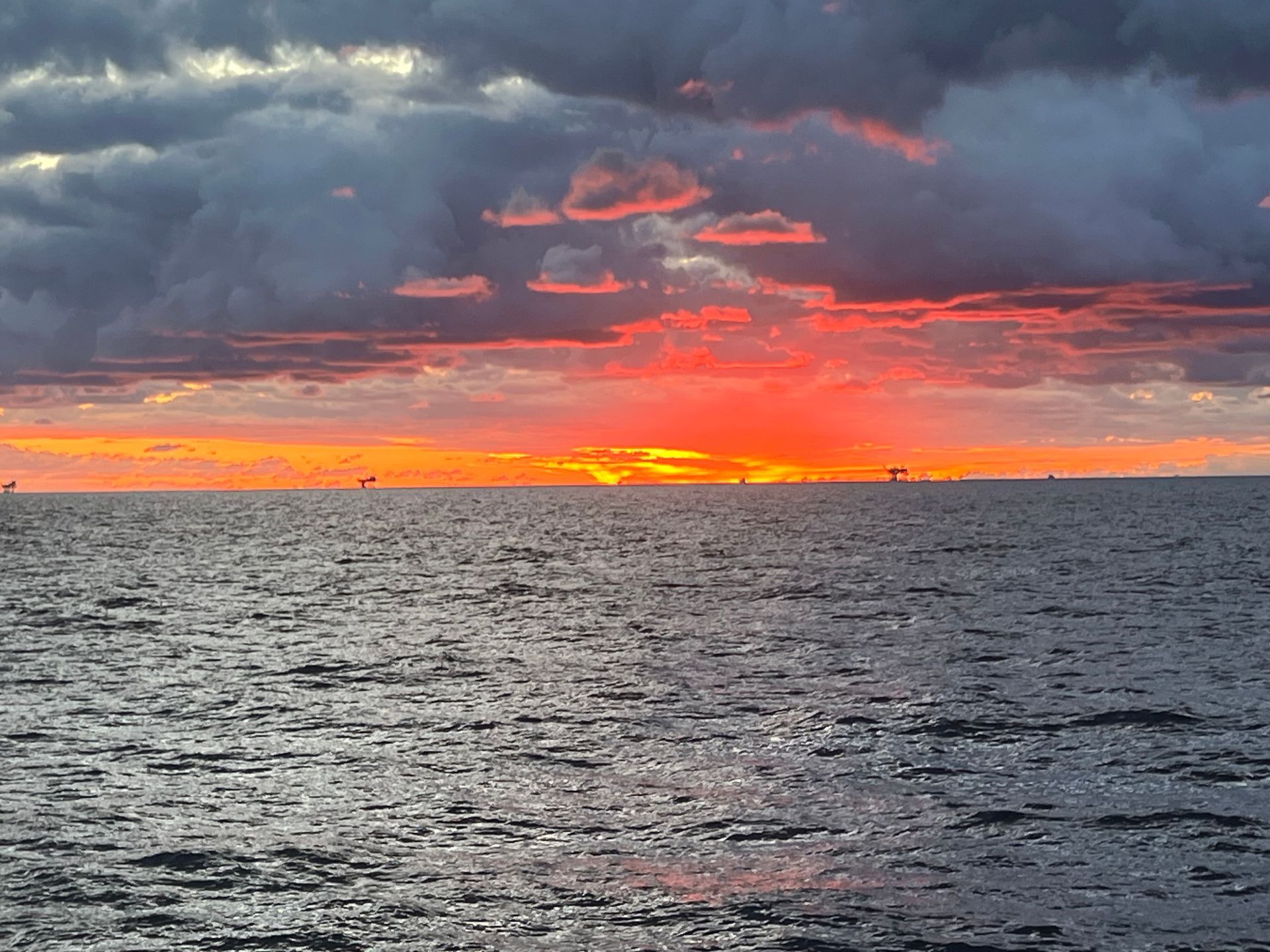 A sunset over the ocean with boats in the distance