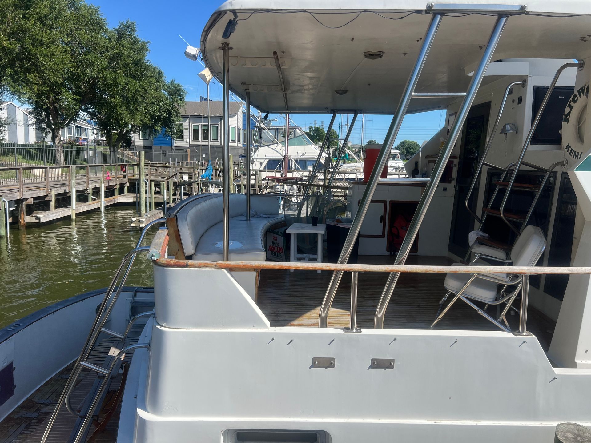A boat is docked at a dock with a couch and chairs on the deck.